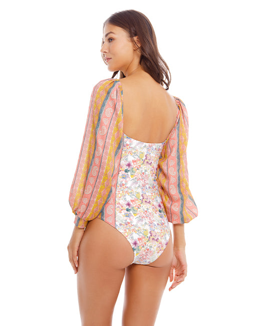 woman wearing a colorfull printed one piece swimsuit with bishop style sleeves and handmade beading at the neckline