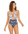 woman wearing a white and blue printed one piece swimsuit with open details upfront